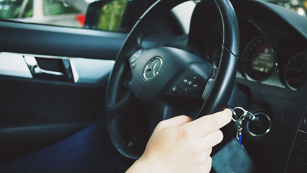 A skilled driver confidently holds the wheel of a Mercedes-Benz, ensuring a Professional Safe Driver experience with safety and expertise.